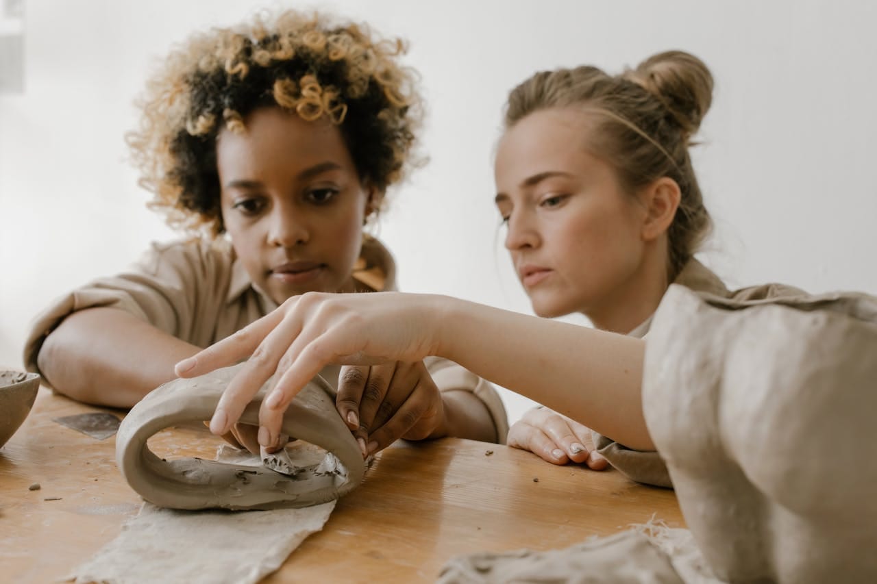 Two focused women crafting pottery pieces in a creative ceramics class.