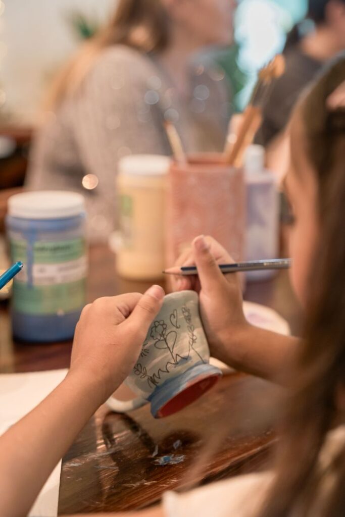 Çocuk sanat atölyesinde seramik obje boyayan çocuk